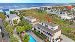 Un quartier résidentiel situé sur la côte, avec une grande maison dotée d’une piscine et offrant une vue sur la plage.