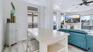 Un salon moderne avec une table blanche, un canapé turquoise et un ventilateur de plafond.