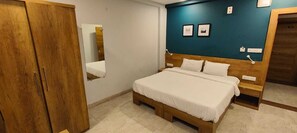 Un dormitorio con una cama de madera, un armario, un espejo y una pared de acento color verde azulado con cuadros enmarcados.