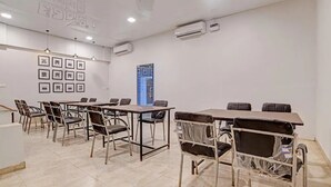 A conference room with a long table and chairs, air conditioning units, and framed pictures on the wall. - Hotel Rush Imperial (Indore)