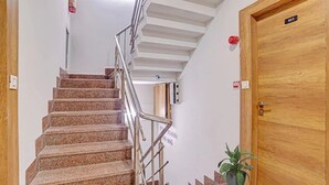 A staircase with metal railings leading to a wooden door labeled "101". - Hotel Rush Imperial (Indore)