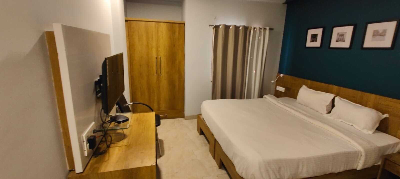 Une chambre d’hôtel comprenant un lit, un bureau avec un ordinateur, une armoire et un téléviseur.