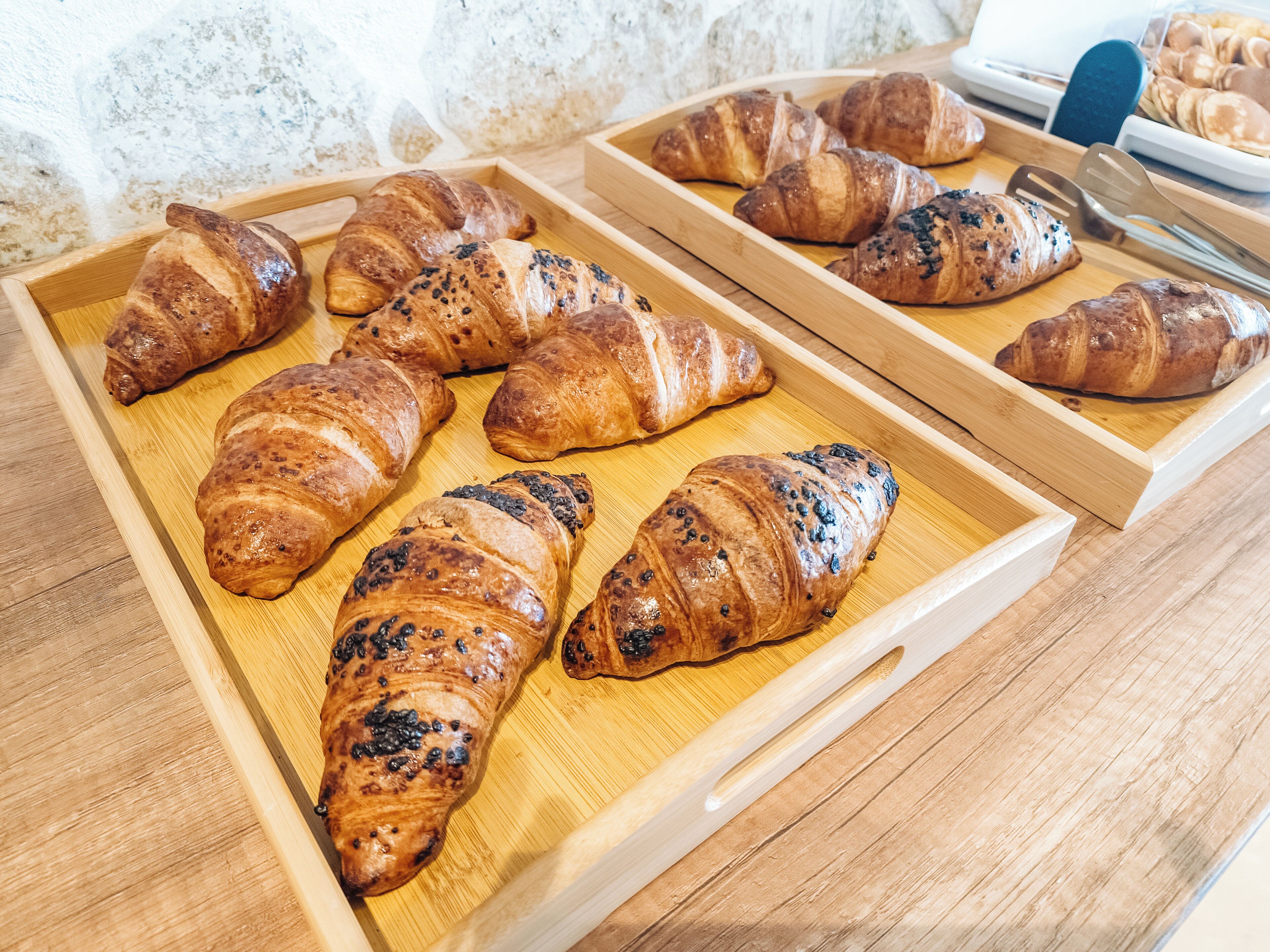 Ein Holztablett mit mehreren Croissants auf einem Tisch.