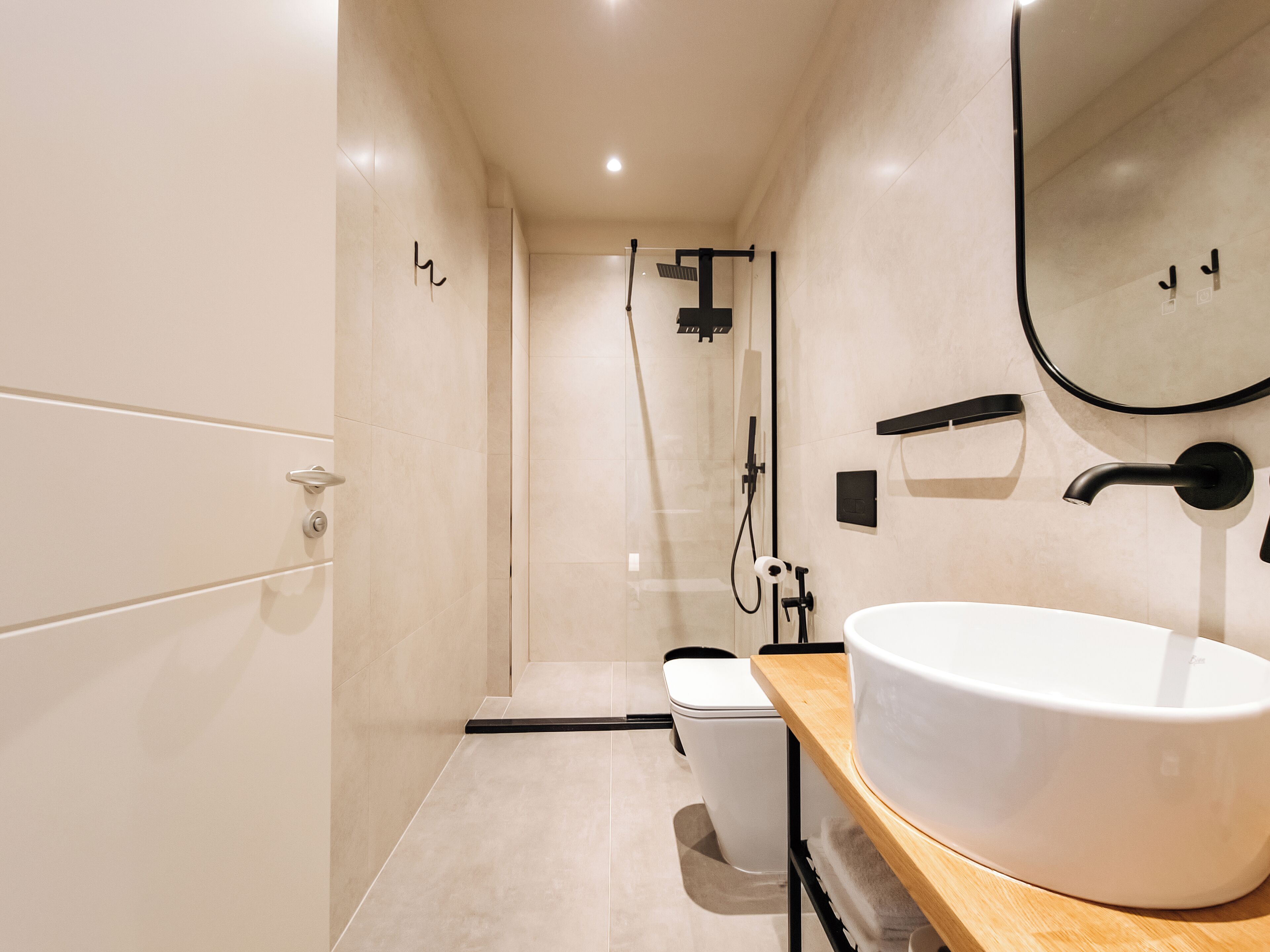 A modern bathroom with a large white sink, a toilet, and a shower area.