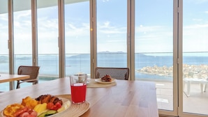 A dining area with a table set for two, a plate of food, and a glass of red drink. - Sunset Shoreline Saranda Hotel (Sarandë)
