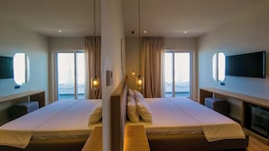 A modern hotel room with two beds, a large window with a view, and a flat-screen TV mounted on the wall. - Sunset Shoreline Saranda Hotel (Sarandë)