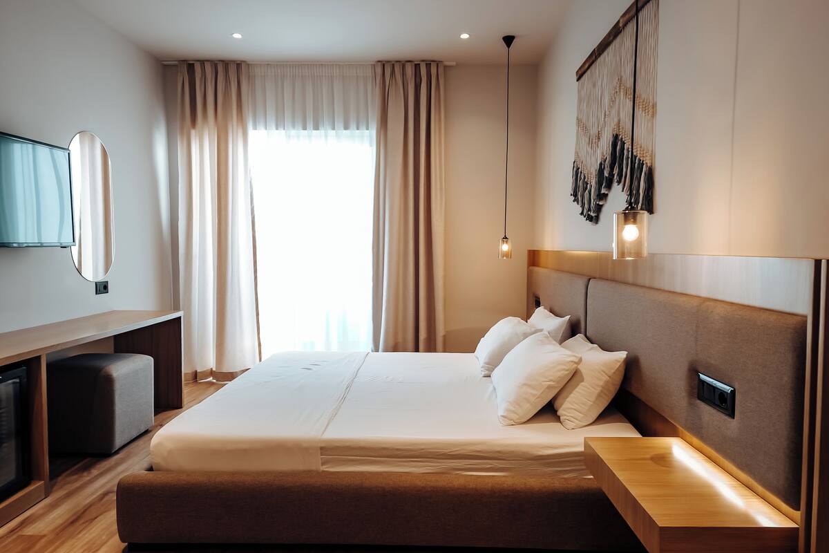A modern hotel room with a large bed, a desk, and a TV.