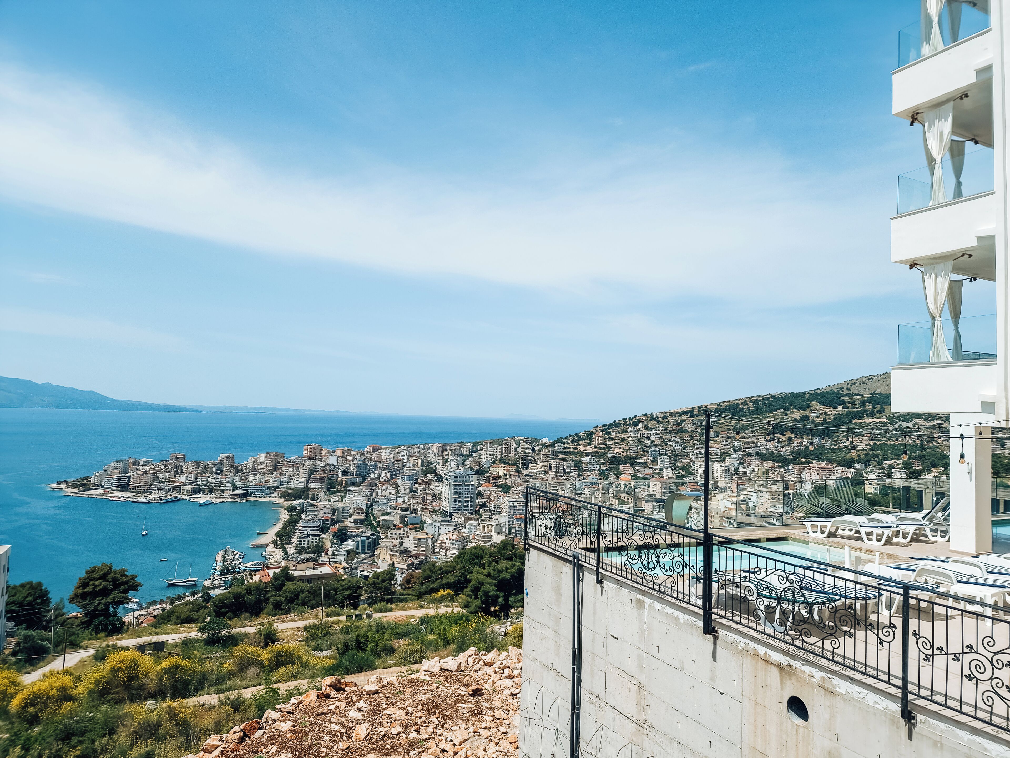 A coastal cityscape with a view of the sea and a modern building with balconies.