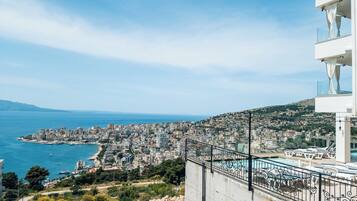 A coastal cityscape with a view of the sea and a modern building with balconies.