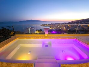 A rooftop pool with a city view, a glass railing, and a sunset in the background. - Sunset Shoreline Saranda Hotel (Sarandë)