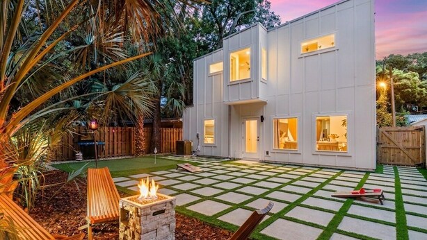 A modern two-story house with a paved patio, outdoor seating, and a fire pit. - St. Augustine 3BR Retreat · 2 King Suites · Putting Green · 1 Mi. to Downtown (St. Augustine)