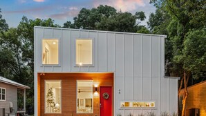 A modern two-story house with a red door, large windows, and a small porch area. - St. Augustine 3BR Retreat · 2 King Suites · Putting Green · 1 Mi. to Downtown (St. Augustine)
