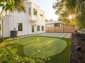 A modern house with a well-maintained lawn, a wooden fence, and a hammock.
