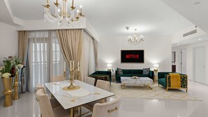 Un saló modern amb zona de menjador, un sofà verd i una televisió que mostra 'NETFLIX'.
