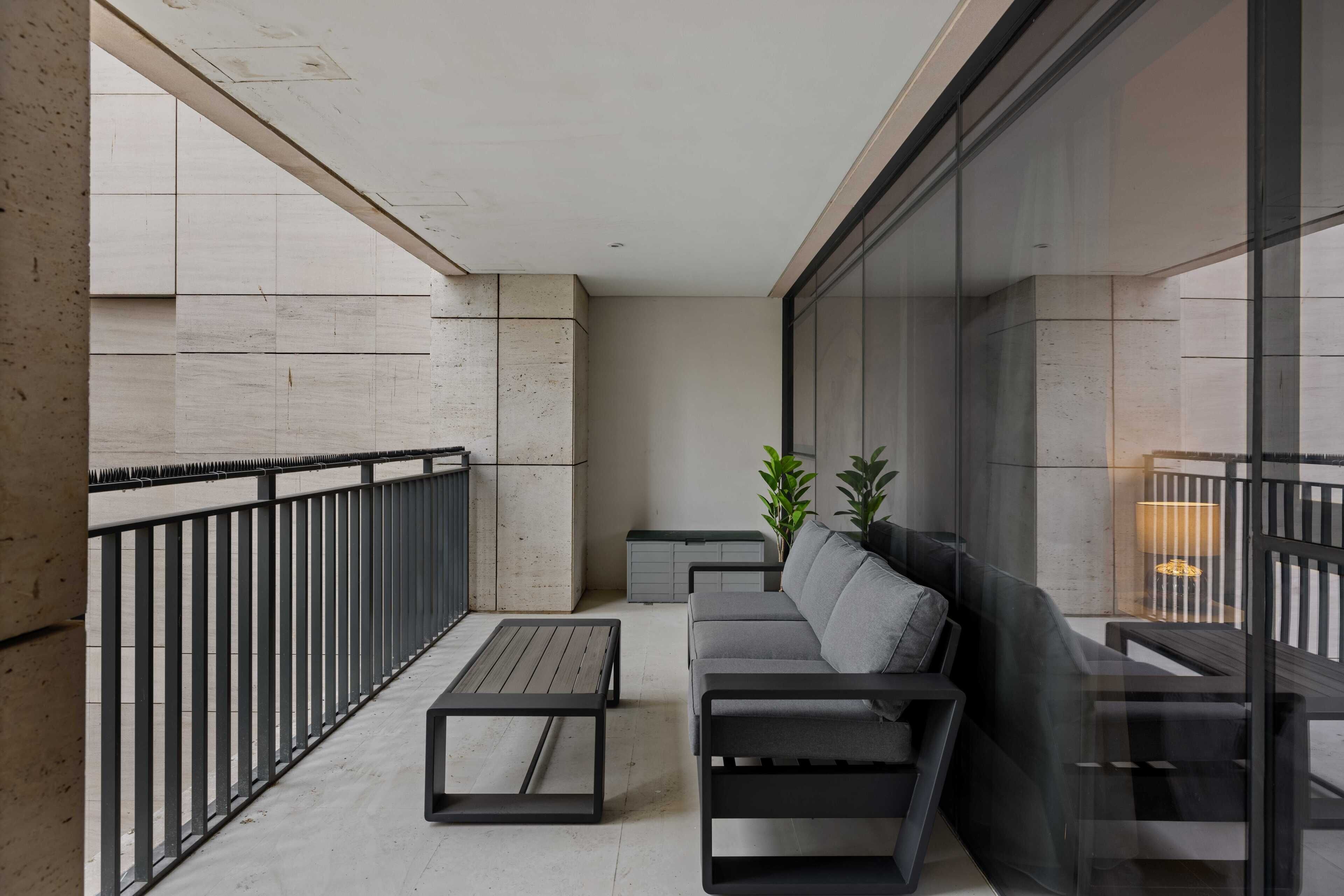 A modern balcony with a sofa, a table, and a lamp.
