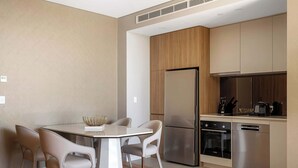 Une cuisine moderne équipée d’un réfrigérateur, d’un four et d’un lave-vaisselle en acier inoxydable. On y trouve une table à manger avec quatre chaises et un vase.