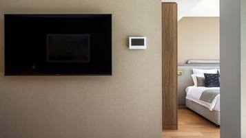 Une chambre à coucher avec un lit, un téléviseur fixé au mur et un thermostat.