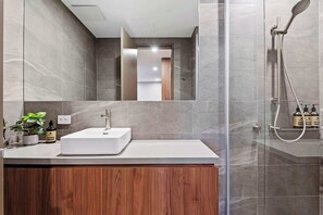 A modern bathroom with a large mirror, a white sink, and a shower area.