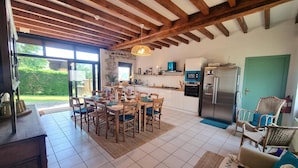 A spacious kitchen with a dining area, wooden beams on the ceiling, and a view of the outdoors. - Quiet cottage with terrace, pets welcomed, near pony farm (Virigneux)