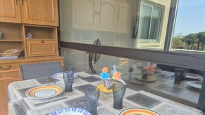 A dining table set with plates, glasses, and a vase with flowers. - Cozy 1BR Apt with Terrace, 4 Sleepers, Near Beach and Port, Parking Included (Cap d'Agde)