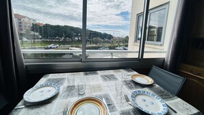 A dining table set with plates, glasses, and cutlery, viewed through a window overlooking a street with buildings and parked cars. - Cozy 1BR Apt with Terrace, 4 Sleepers, Near Beach and Port, Parking Included (Cap d'Agde)