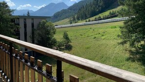 A train passing through a mountainous area with a building in the foreground. - Charming renovated studio with balcony and WIFI, near the slopes (Pra-Loup)