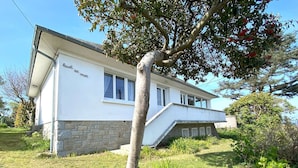 A modern two-story house with a stone foundation and white exterior walls.