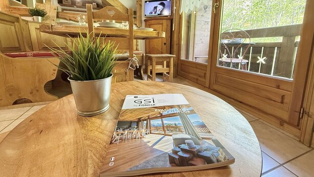 A wooden interior with a dining area, a television, and a window with a view of the outdoors. - Mezzanine Studio with Balcony, Near Ski Shuttle & Swimming Lake - Sleeps 6 (Praz-sur-Arly)