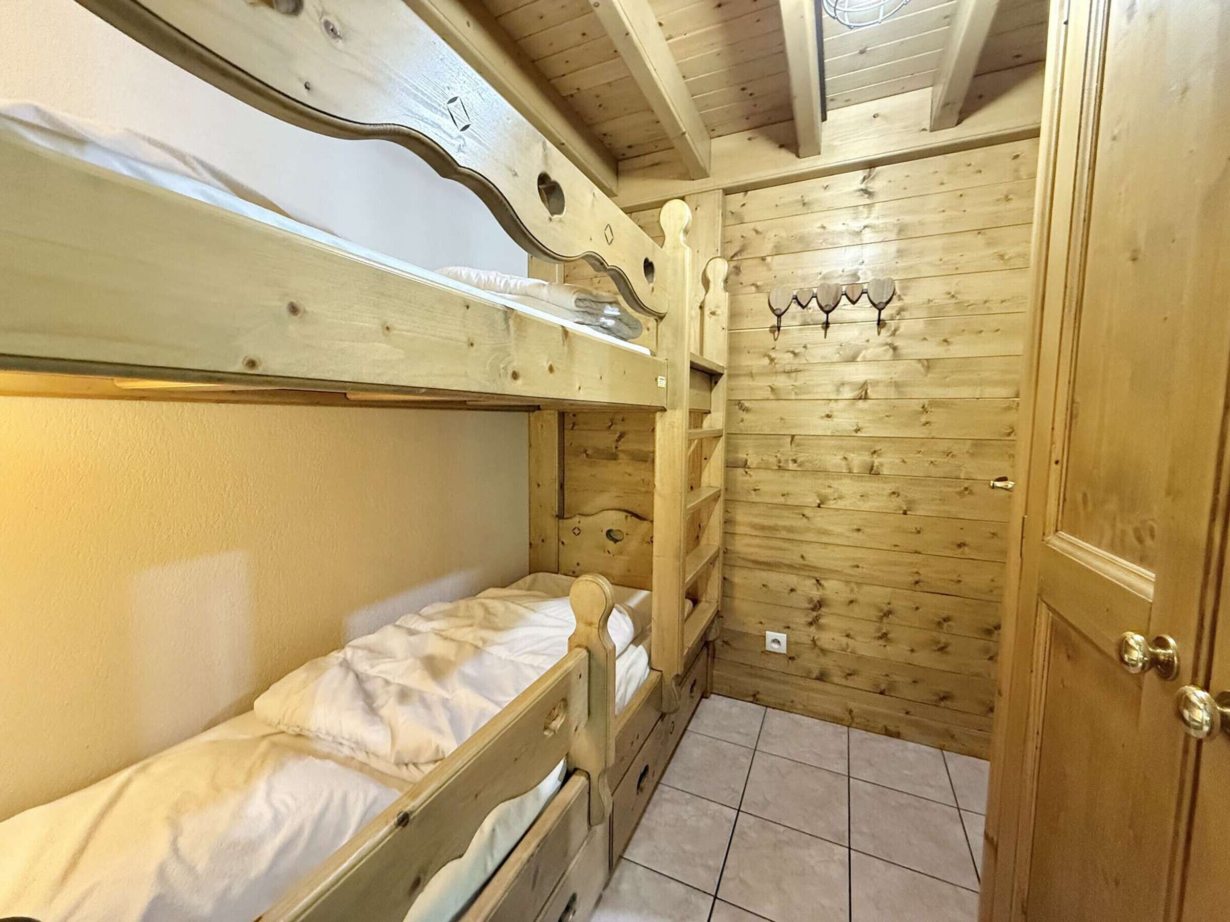 A small, wooden room with bunk beds and a wooden door.