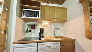 A compact kitchen with a Bosch dishwasher, a Liebherr refrigerator, a microwave, and a coffee maker. - Mezzanine Studio with Balcony, Near Ski Shuttle & Swimming Lake - Sleeps 6 (Praz-sur-Arly)