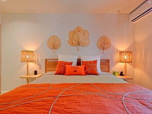 A neatly made bed with a red and white patterned bedspread, flanked by two bedside tables with lamps, and three wall-mounted decorative fans.