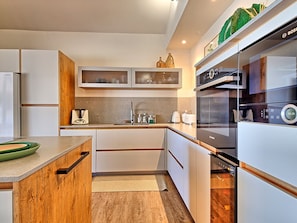 A modern kitchen with white cabinets, a wooden countertop, and a Bosch oven.