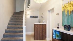 A staircase with carpeted steps leading to a landing with a reception desk. - Putera Puteri Residence (London)