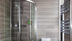 A modern bathroom with a glass-enclosed shower, a toilet, and a built-in sink. - Putera Puteri Residence (London)