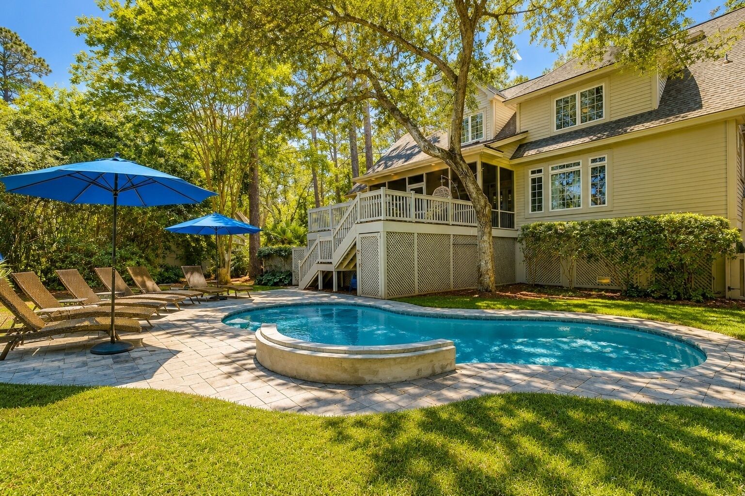 Un patio trasero con piscina, sillas de descanso y una terraza de madera.