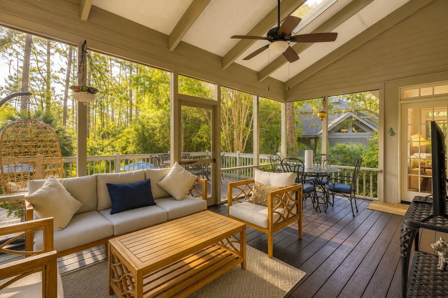 A covered outdoor patio with a sofa, chairs, a table, and a ceiling fan.