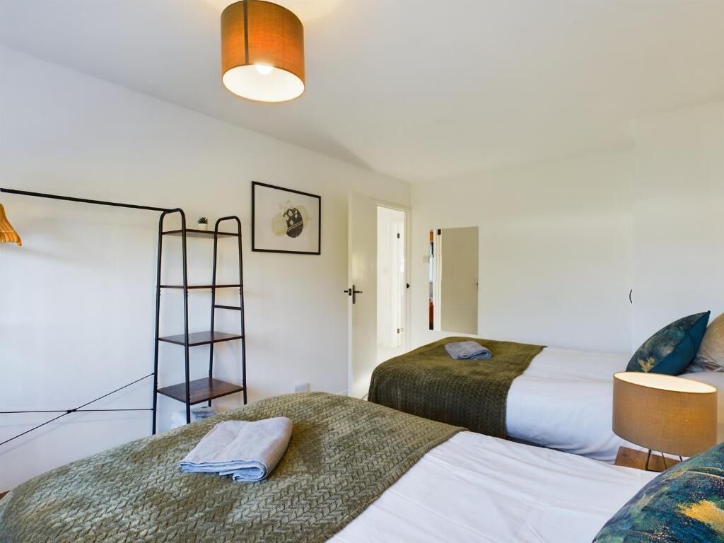 A hotel room with two beds, a ladder, a lamp, and a door leading to another room.