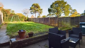 Ein Garten mit Rasenfläche, Holzzaun und Gartenmöbeln.