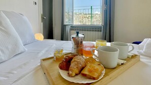 A neatly made breakfast tray with croissants, toast, and a drink on a hotel bed. - Happy Family Apartments Panorama (Genoa)