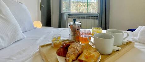 A neatly made breakfast tray with croissants, toast, and a drink on a hotel bed.
