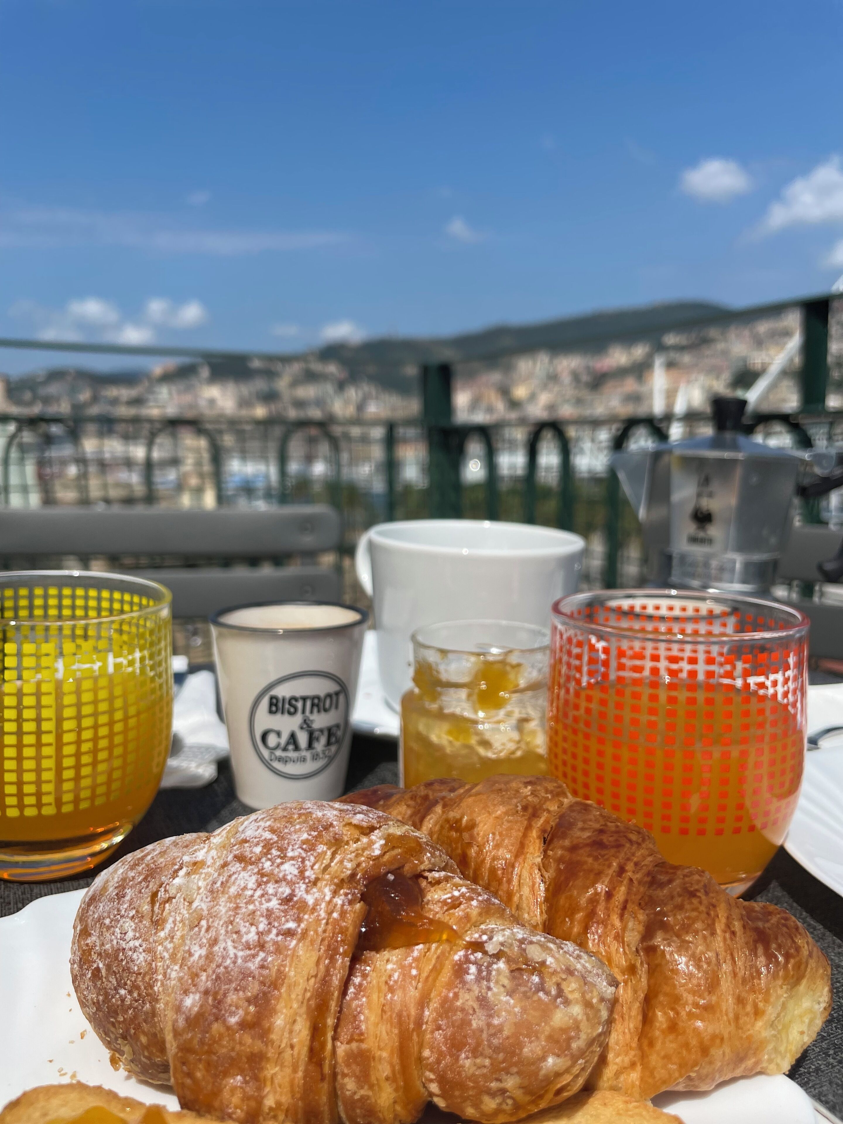 A breakfast tray with croissants and honey-glazed pastries, a candle labeled 'BISTROT & CAFE', and two glasses of honey.