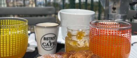 A breakfast tray with croissants and honey-glazed pastries, a candle labeled 'BISTROT & CAFE', and two glasses of honey.