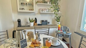 A breakfast setting with a table set for two, including croissants, coffee, and orange juice. - Happy Family Apartments Panorama (Genoa)