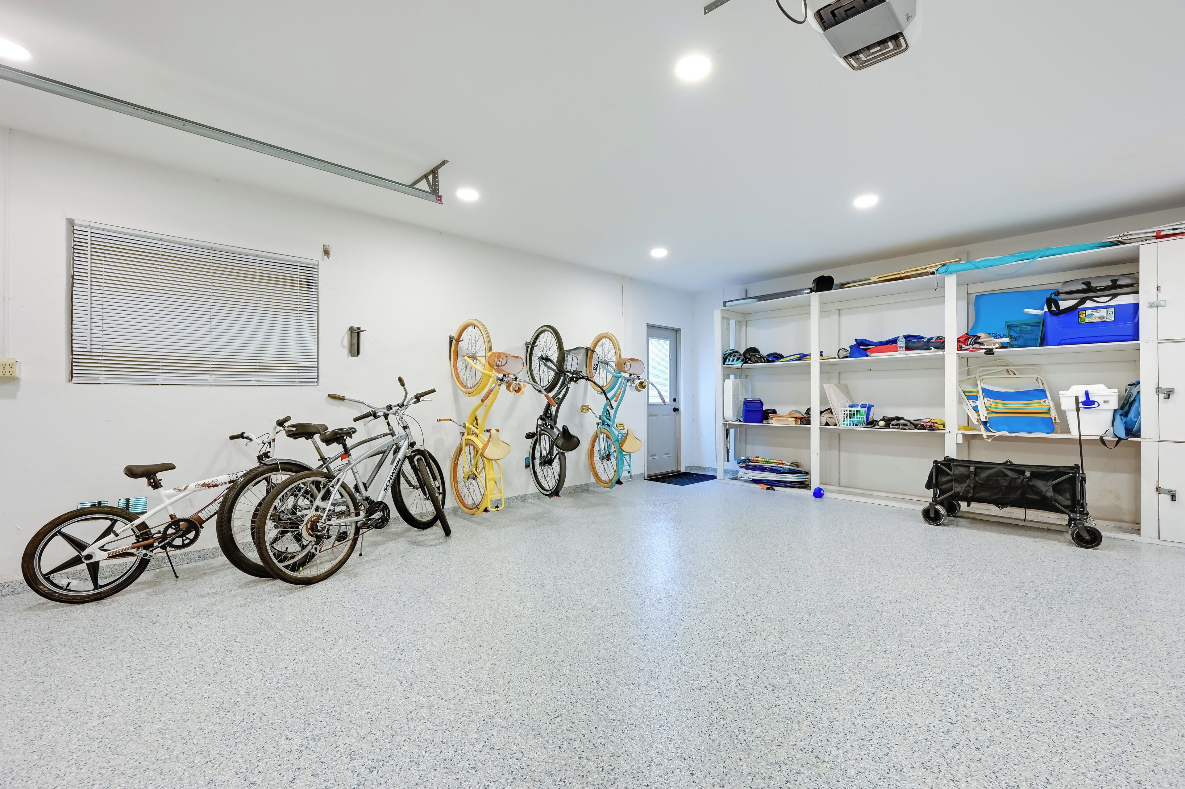 A clean, well-lit room with bicycles, shelves with sports equipment, and a projector on the ceiling.