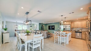 A spacious kitchen with modern appliances, a dining area with white chairs, and a cozy living space with a sofa and a coffee table. - Marco Island Family Home: Pool, Lanai, Backyard! (Marco Island)