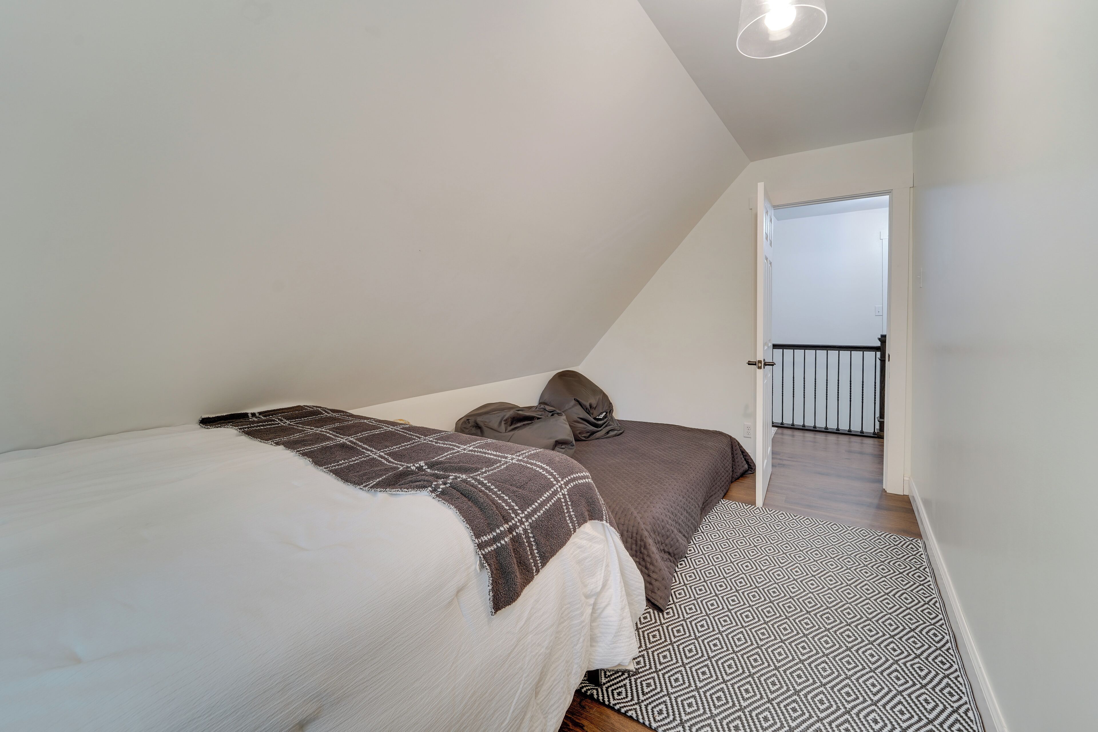 Une chambre à coucher avec un lit, deux oreillers, une couverture et un tapis à motifs.