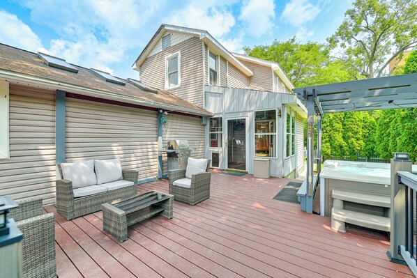 Una terraza techada con mobiliario de mimbre, un jacuzzi y un pérgola.