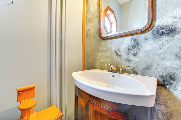 A bathroom with a white sink, wooden cabinet, and a mirror with a wooden frame.