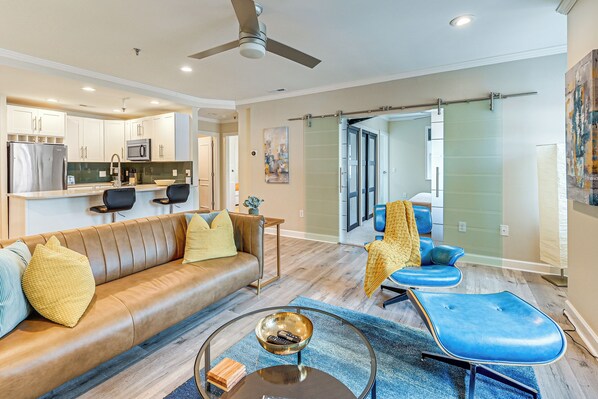 A modern living room with a leather sofa, a blue armchair, and a coffee table. - Charming Apartment in Downtown Winston-salem! (Winston-Salem)
