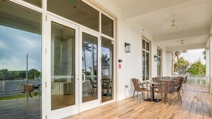 A covered outdoor area with a wooden deck, glass sliding doors, and a table with chairs. - Pool, Golf & Beach Access: Fort Pierce Condo! (Fort Pierce)